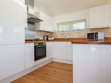 A kitchen with white cabinets wooden countertops a stainless steel oven toaster kettle and microwave at 5 Meadow Retreat in Dobwalls