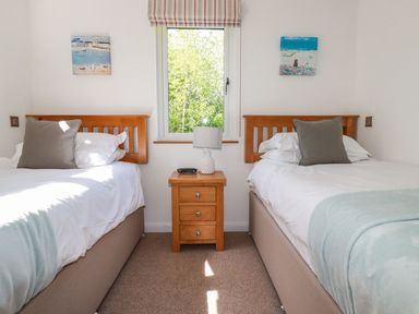 A bedroom with two single beds and a wooden nightstand between them at 5 Meadow Retreat in Dobwalls
