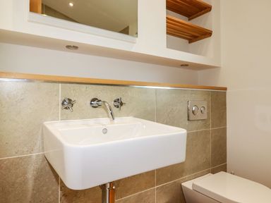 A bathroom sink with wall-mounted taps and a toilet with flush buttons at 5 Meadow Retreat in Dobwalls