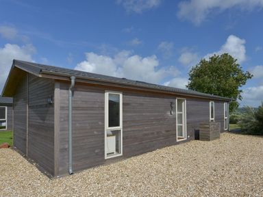 A single story wooden house with small windows on a gravel ground under a blue sky at 10 Horizon View in Dobwalls