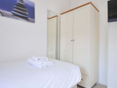 A bedroom with a bed, wardrobe, mirror and towels at 10 Horizon View in Dobwalls