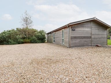 A wooden building with gravel ground and bushes in the background at 11 Horizon View in Dobwalls