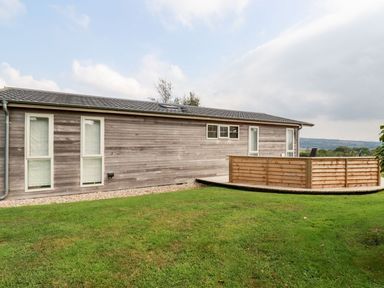 An exterior view of a wooden house with multiple windows and a small fenced deck on a grass lawn at 11 Horizon View in Dobwalls
