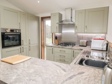 A kitchen with built-in oven stove sink and countertop at 2 Meadow Retreat in Dobwalls