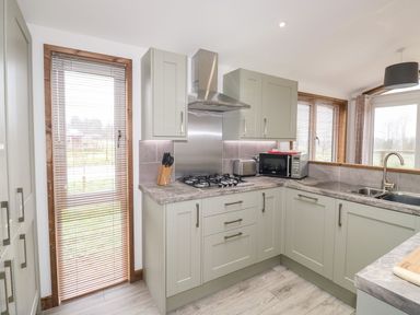 A kitchen with cabinets a gas stove a microwave and a sink at 2 Meadow Retreat in Dobwalls