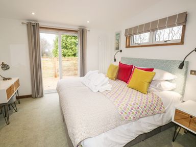 A bedroom with a bed with colorful pillows and a small table with a lamp at 2 Meadow Retreat in Dobwalls