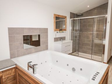A bathroom with a large bathtub, a shower enclosure with glass doors, sink with vanity and a mirror at 2 Meadow Retreat in Dobwalls