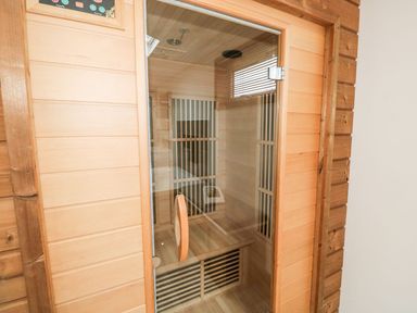 A wooden sauna room with a glass door and a control panel at 2 Meadow Retreat in Dobwalls