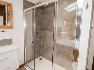 A bathroom with a glass shower enclosure tiled walls a white vanity with drawers and a wooden framed mirror at 2 Meadow Retreat in Dobwalls