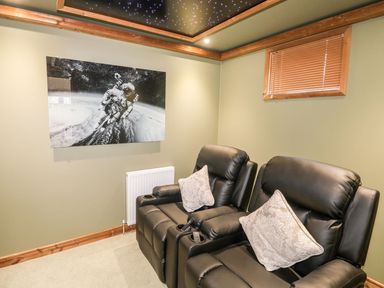 A room with two black leather recliners and a space-themed wall picture at 2 Meadow Retreat in Dobwalls