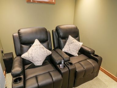Two black leather recliner chairs with patterned cushions and remote controls in a room at 2 Meadow Retreat in Dobwalls