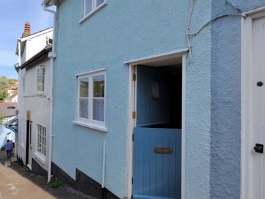 A street view of houses with a blue half door open at 30 Sherborne Lane Lyme Regis