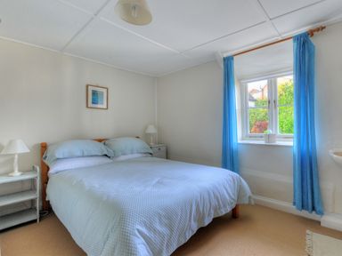 A bedroom with a bed two bedside tables lamps blue curtains and a window at 30 Sherborne Lane Lyme Regis