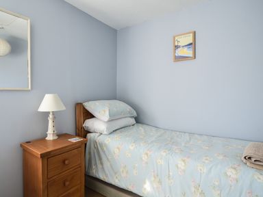 A bedroom with a single bed with floral bedding and a wooden bedside table with a lamp at 30 Sherborne Lane in Lyme Regis