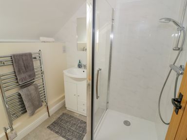 A bathroom with a shower enclosure a sink with cabinet a towel rack and a small rug at The Granary in Little Dasset near Gaydon