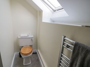 A small bathroom with a toilet wooden seat a towel rack and a skylight window at The Granary in Little Dasset near Gaydon