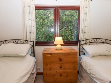 A bedroom with two single beds a wooden chest with a lamp under a window at Dartmoor Retreat Lodge Clifford Bridge near Moretonhampstead