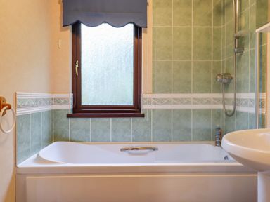 A bathroom with a bathtub shower sink and window at Dartmoor Retreat Lodge Clifford Bridge near Moretonhampstead