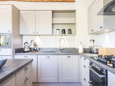 A kitchen with a sink in the center on a gray countertop with white cabinets and a gas stove on the right at Chestnut Lodge in Teigngrace near Newton Abbot