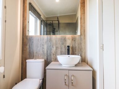 A bathroom with a toilet a sink on a vanity and a large mirror above at Chestnut Lodge in Teigngrace near Newton Abbot