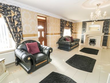 A living room with black leather sofas and a fireplace at Bryn Berthen in Penrhyndeudraeth