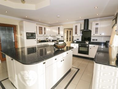 A kitchen with a large island and black countertops at Bryn Berthen in Penrhyndeudraeth