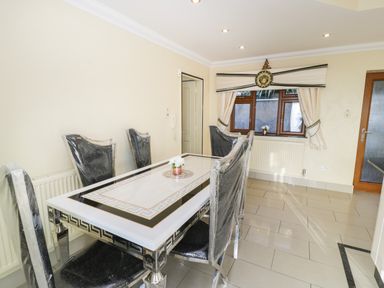 A dining room with a decorated table and six chairs covered in plastic at Bryn Berthen in Penrhyndeudraeth