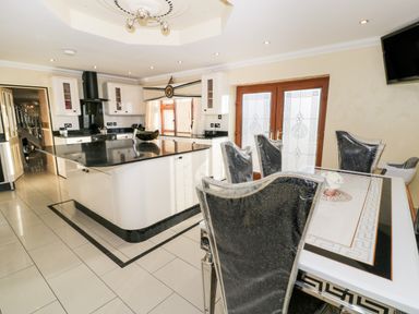 A kitchen with a central island and dining table with chairs in Bryn Berthen Penrhyndeudraeth