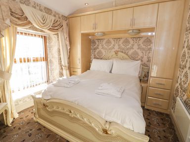 A bedroom with a double bed and overhead cabinets near a window at Bryn Berthen in Penrhyndeudraeth