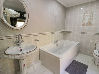 A bathroom with a pedestal sink a bathtub and a toilet at Bryn Berthen in Penrhyndeudraeth