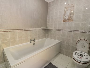 A bathroom with a bathtub and a toilet with a Chanel branded seat cover at Bryn Berthen in Penrhyndeudraeth
