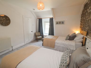 A bedroom with two beds a chair curtains and a door at Delfryn Newport