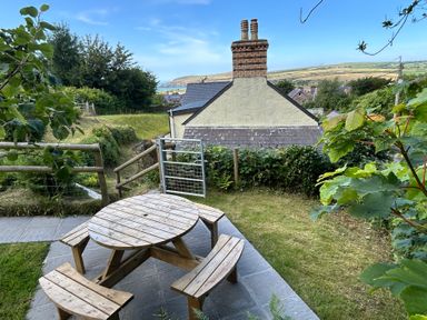 A garden with a wooden table and benches at Delfryn, Newport