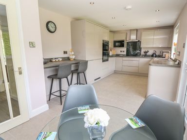 A kitchen with a glass table and grey chairs and bar stools at Erwlon in Rhydyfelin near Aberystwyth