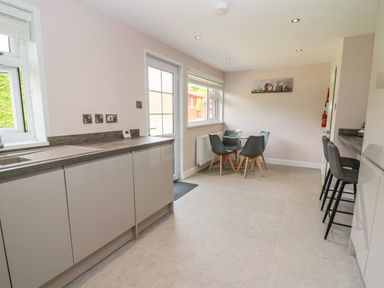 A kitchen with a countertop sink dining table with four chairs and two bar stools at Erwlon in Rhydyfelin near Aberystwyth