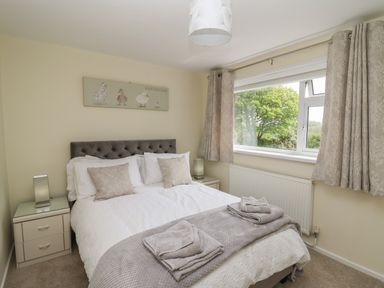 A bedroom with a double bed two bedside tables and a window with curtains at Erwlon in Rhydyfelin near Aberystwyth