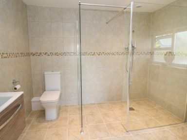A bathroom with a toilet a shower area with glass partition and a window at Erwlon in Rhydyfelin near Aberystwyth