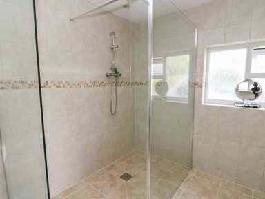 A walk in shower with tiled walls and floor and a frosted window at Erwlon in Rhydyfelin near Aberystwyth