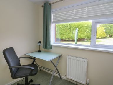 A small office corner with a black chair a glass desk and a window at Erwlon in Rhydyfelin near Aberystwyth