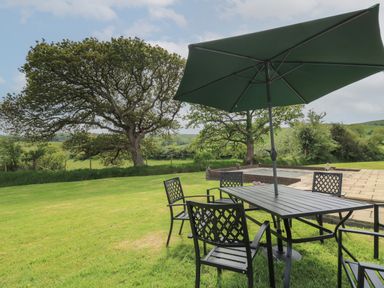 A garden with a metal table and chairs under an umbrella at Erwlon in Rhydyfelin near Aberystwyth