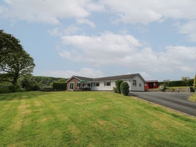 A single story house with a large lawn and a driveway at Erwlon in Rhydyfelin near Aberystwyth