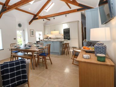 An open kitchen and dining area with wooden beams and table at Fron Olau in Nefyn