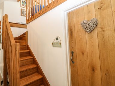 A wooden staircase next to a wooden door with a heart decoration at Fron Olau in Nefyn