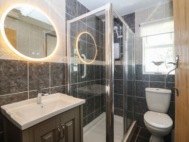 A bathroom with a sink cabinet mirror shower enclosure and toilet at Fron Olau in Nefyn