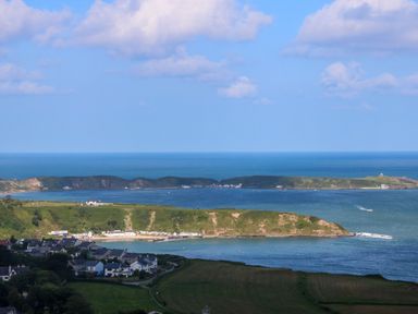 A coastal village with houses near a bay and hills in the background at Fron Olau in Nefyn