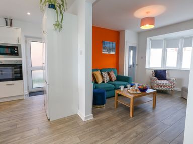 A living room with a blue sofa with cushions a wooden coffee table and a patterned armchair by a window at Lagoon View in Wyke