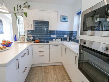 A kitchen with white cabinets blue tiled backsplash and stainless steel appliances at Lagoon View in Wyke