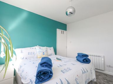 A bedroom with a bed dressed in nautical printed bedding and two rolled blue towels on the bed at Lagoon View in Wyke