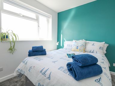 A bedroom with a bed covered with nautical themed bedding and blue towels on top at Lagoon View in Wyke