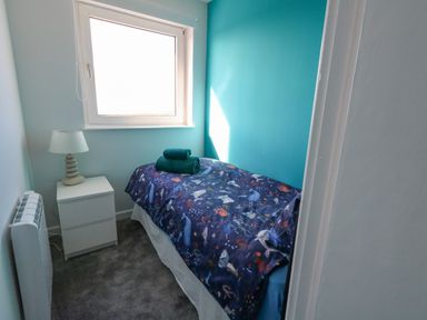 A small bedroom with a single bed a nightstand with a lamp and a window at Lagoon View in Wyke